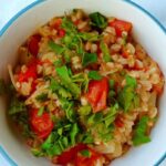 farro with tomatoes, in a bowl, garnished with parsley