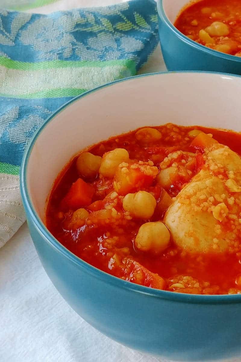 stewed chicken and chickpeas with couscous, in a bowl on a table with a napkin