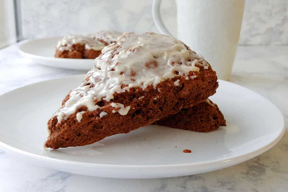 two double chocolate scones, on a plate with a mug nearby