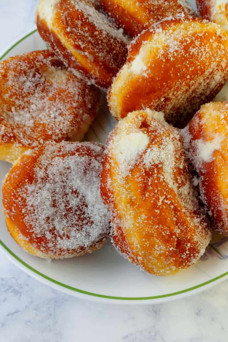 Paczki, covered with granulated sugar, on a large plate