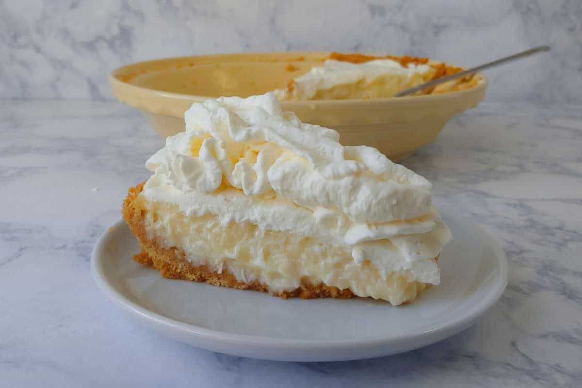 a slice of coconut cream pie, in front of a pie plate